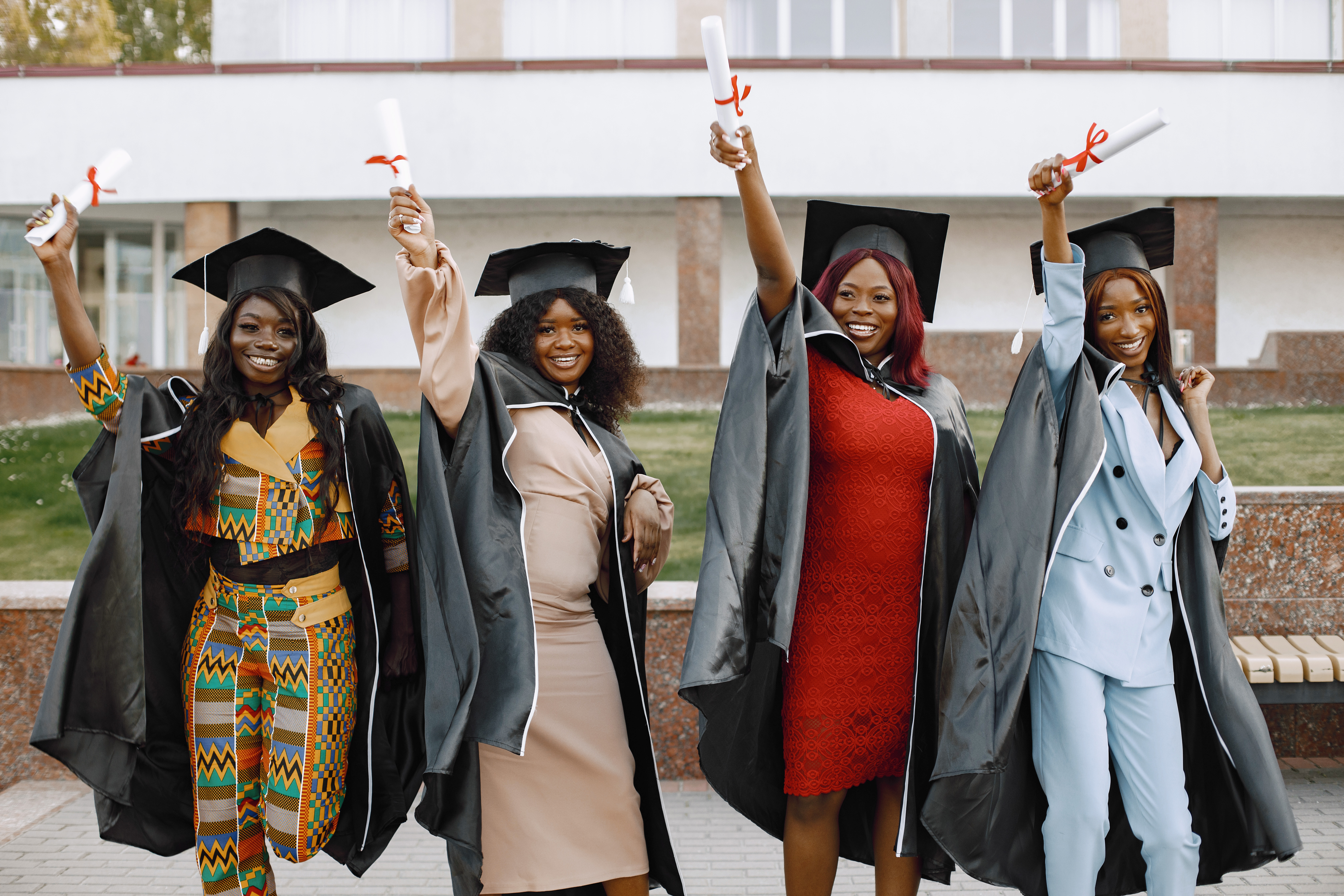 Four Black women holding certificates and dressed in convocation gowns via Freepik