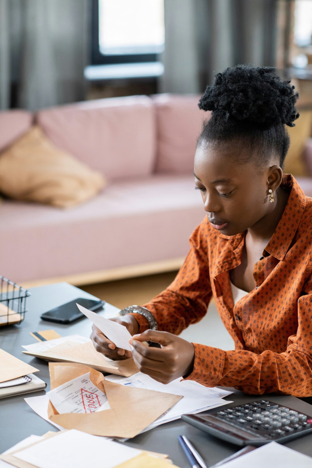 Black woman looking at bills and a calculator by Getty Images via Unsplash
