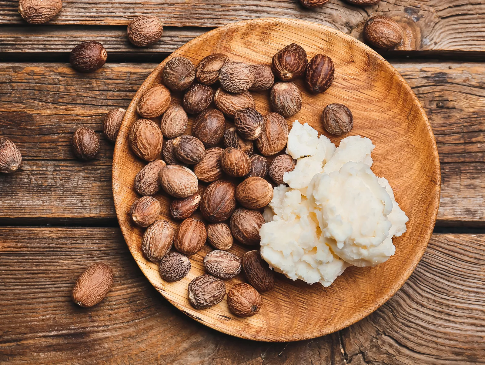 Shea ban; an aerial view of shea seeds and butter in a wooden plate via Britannica.com