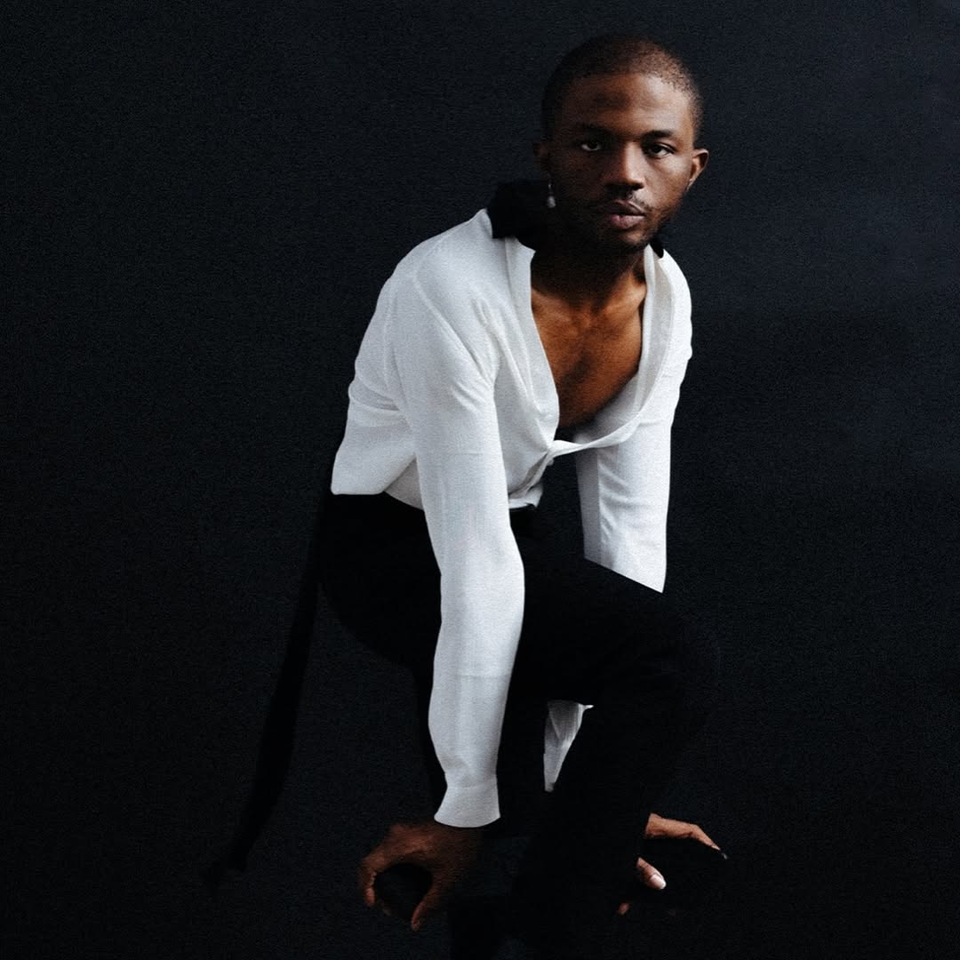 Daniel Obasi posing for a picture in front of a black backdrop 