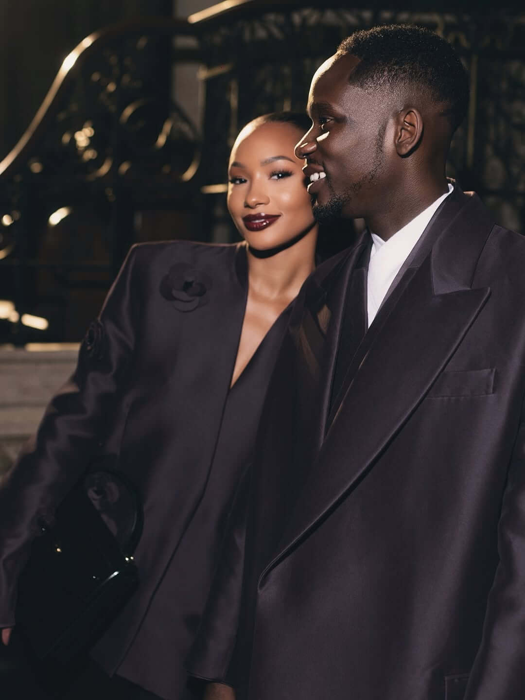 Temi Otedola and Mr Eazi in matching deep plum Casablanca satin suits at Paris Fashion Week.