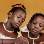 Two girls in uniform writing in a book via Freepik