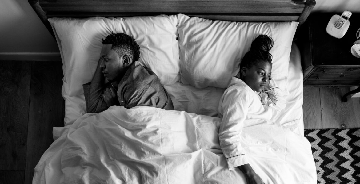 Cheating dreams: A couple backing each other in bed.