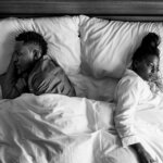 Cheating dreams: A couple backing each other in bed.