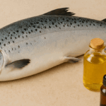 A whole fresh salmon lies on a beige textured surface beside three skincare bottles — one filled with golden oil, one small amber dropper bottle, and one frosted white serum bottle. The fish is positioned diagonally, with its scales glistening under soft lighting.