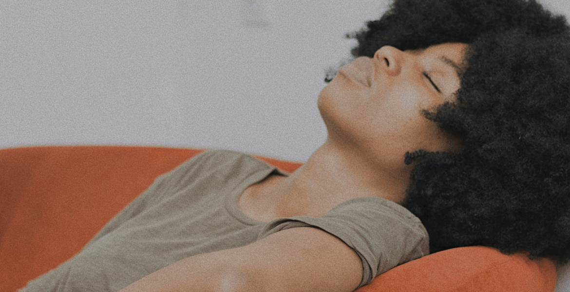 A Black woman laying on a couch by Baptiste Ime via Unsplash+