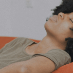 A Black woman laying on a couch by Baptiste Ime via Unsplash+