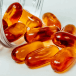 A transparent medicine bottle with amber capsules spewing from it