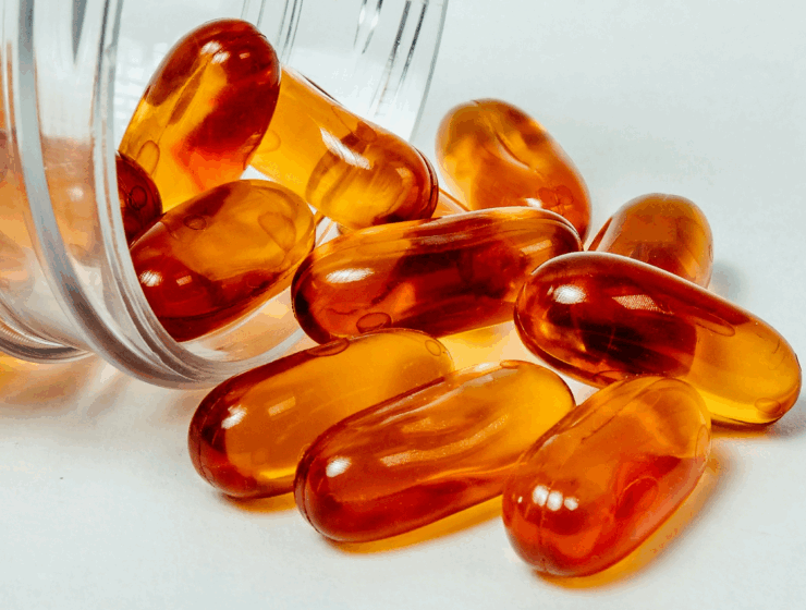 A transparent medicine bottle with amber capsules spewing from it