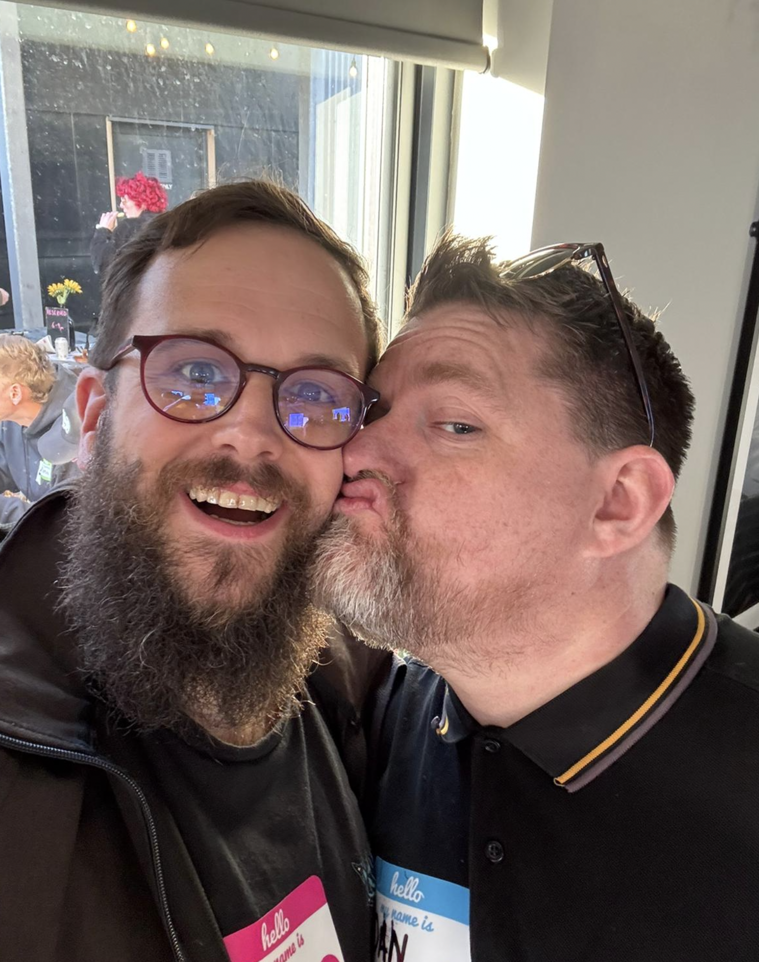 On the left is Chris Chant. On the right is Dan Billing giving Chris a kiss on the cheek. Chris has a big grin.