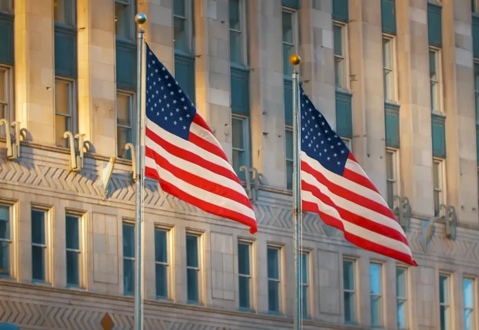 us flags with buildings in background