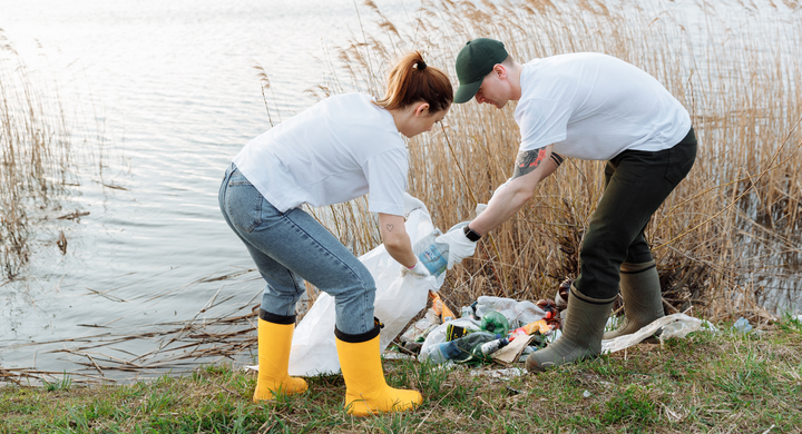 Man and woman cleaning up litter near a river