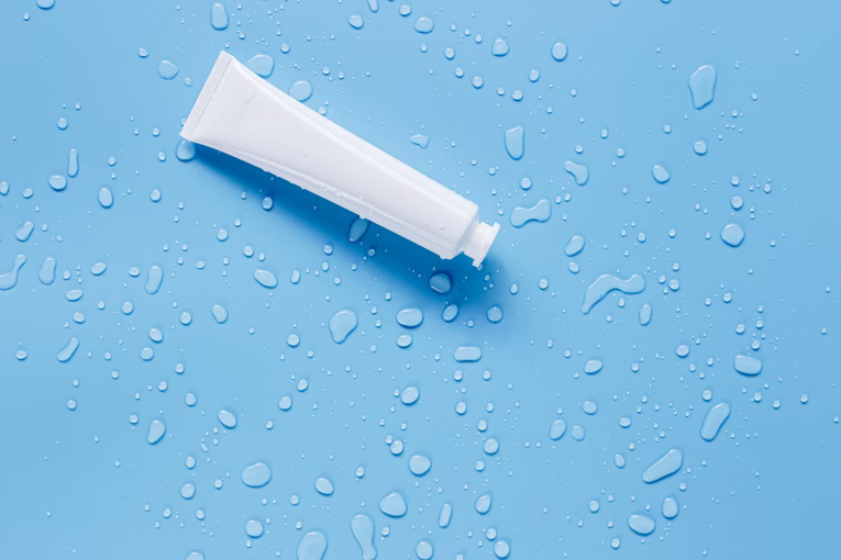 Cosmetic tube on water drop background