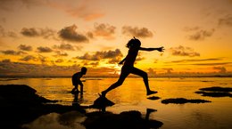 Children playing in sea with sunset in background