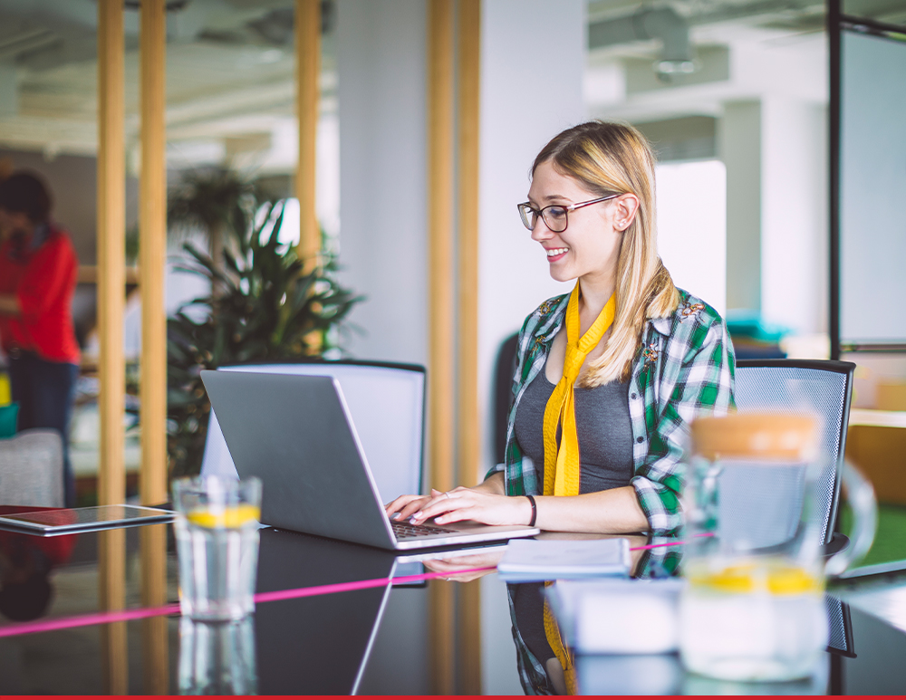 A photo of someone working on a laptop and smiling.