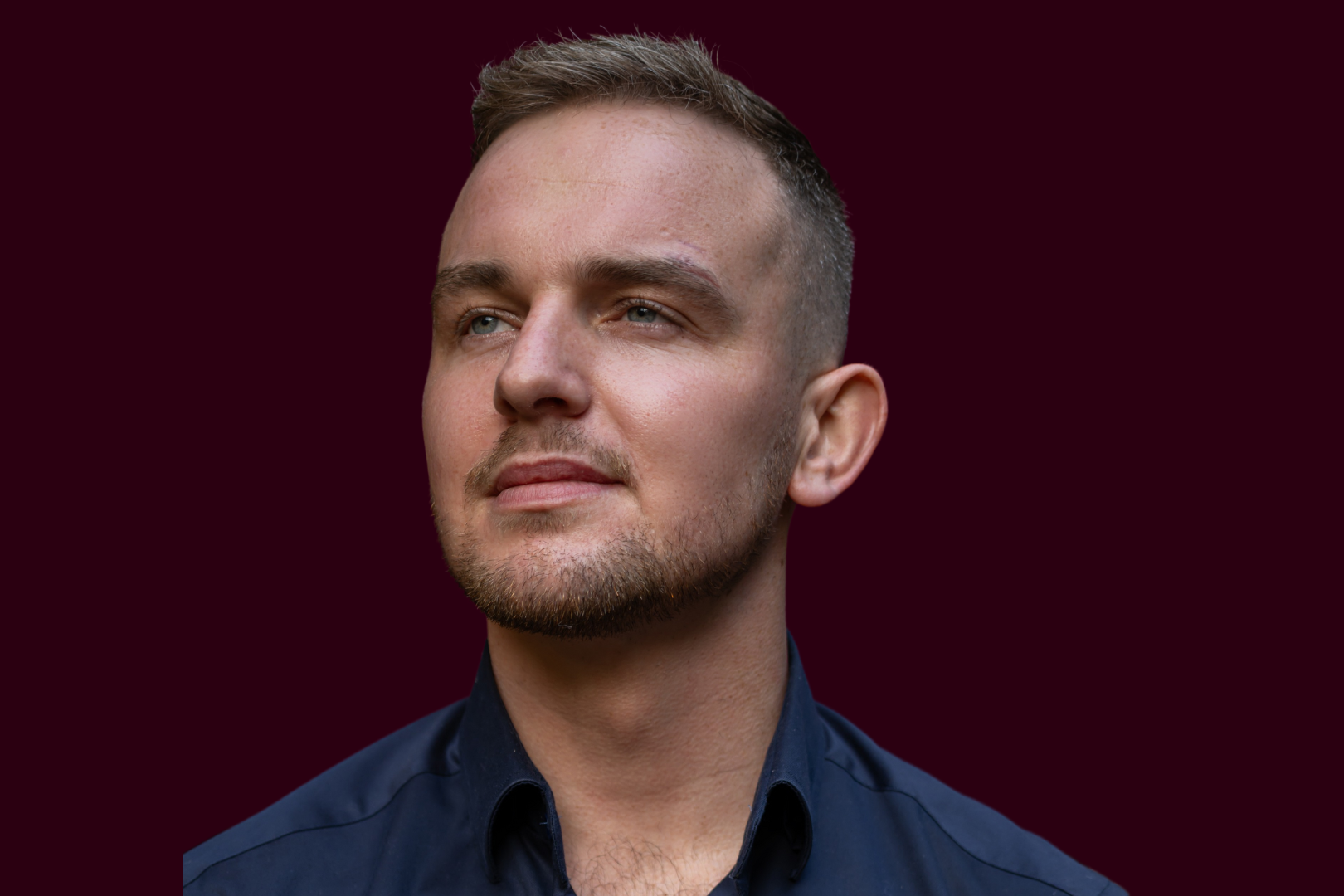 Dan McCabe, Irish folk singer, pictured in a close-up portrait wearing a dark jacket, with a serious expression, set against a soft, blurred background.