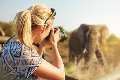 Woman taking a photo of an elephant on safari