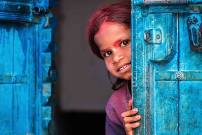 a small girl hiding behind a door in India