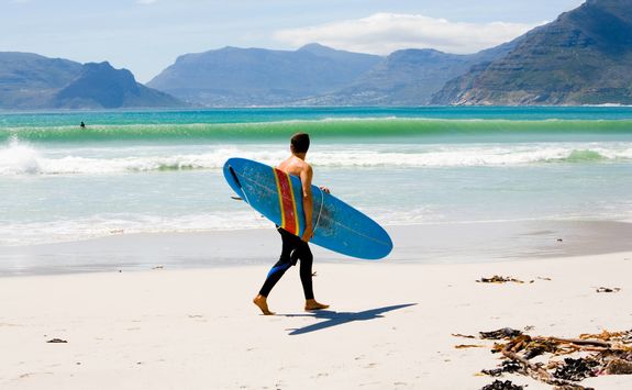 Man with surfboard on Kommetjie beach