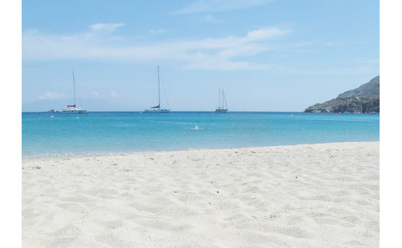Sandy beach and boats in the water in Mykonos