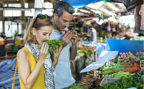 Couple smelling vegetables in a street market