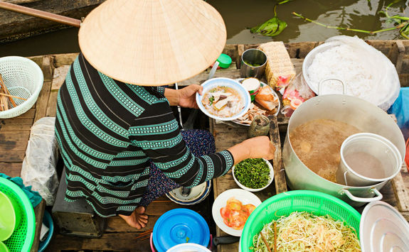 vietnamese woman preparing pho noodle soup on floating boat