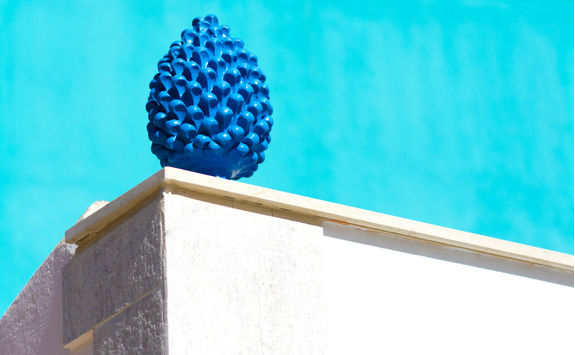 ceramic blue pine cone against turquoise wall