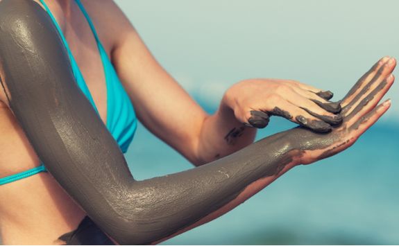 woman smearing mud mask on the body