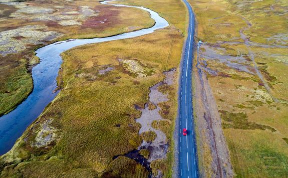 Aerial view of a red car driving on road