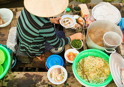 vietnamese woman preparing pho noodle soup on floating boat