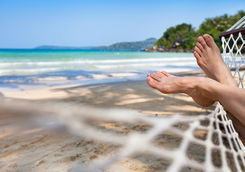 Feet in a hammock on a sand beach
