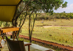 Chairs in front of a canvas tent turned to the savanna