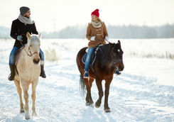 couple horseback riding along snowy trail