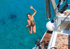 girl jumping off boat into crystal blue waters