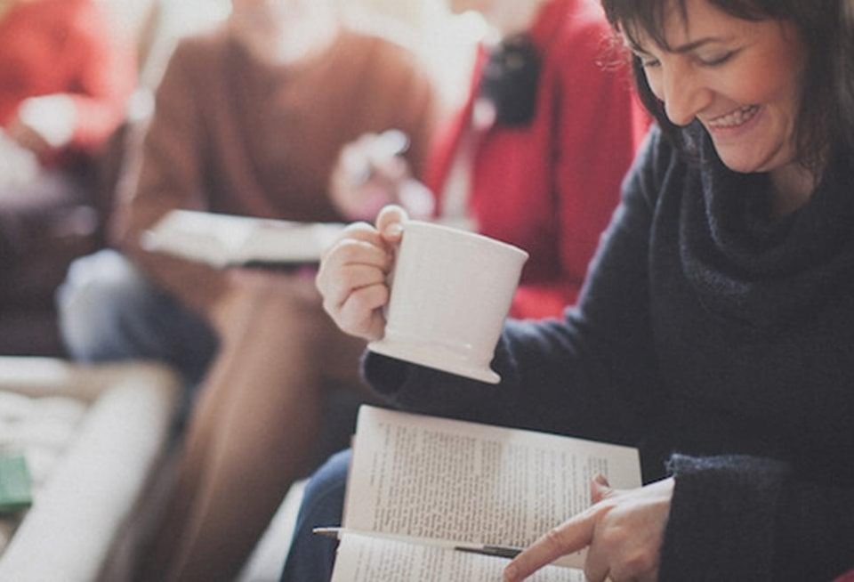 Person reading book with mug
