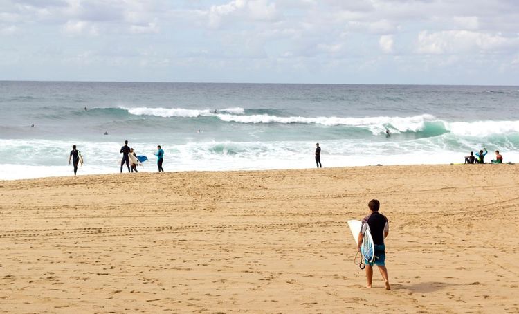 Unrecognizable,Surfer,Holding,His,Surf board,Walking,Towards,The,Sea,At