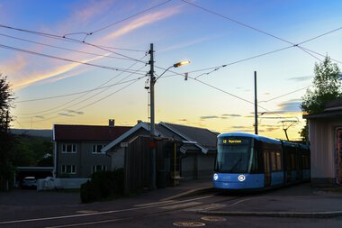 SL18 og bolighus i solnedgang på Kjelsås trikkestopp