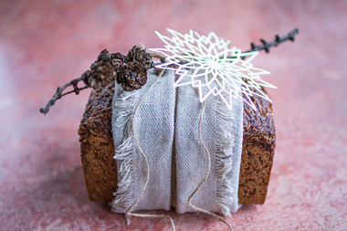 Rugbrød med masse fiber og næring med et linhåndkle brettet som et bredt bånd på midten, med kvist, naturtråd og lekker julepynt.