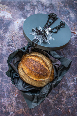 Til mannen med stor M: Røft, rustikk og sprøtt surdeigsbrød i sort eske med sort silkepapir og dekorativ julepynt. 