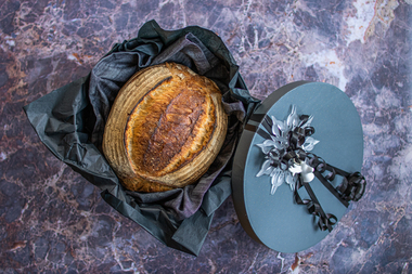 Til mannen med stor M: Røft, rustikk og sprøtt surdeigsbrød i sort eske med sort silkepapir og dekorativ julepynt. 