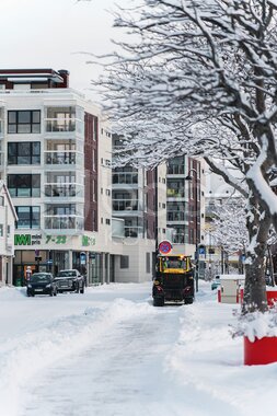 Gravemaskin brøyter snø i sentrum