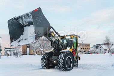 Gravemaskin brøyter snø i sentrum