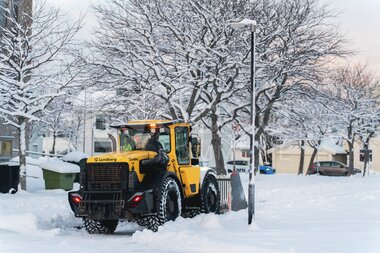 Gravemaskin brøyter snø i sentrum