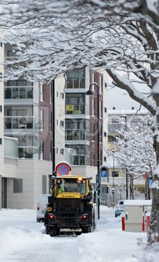 Gravemaskin brøyter snø i sentrum
