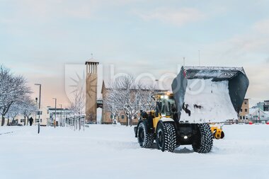 Gravemaskin brøyter snø i sentrum