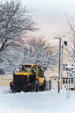 Gravemaskin brøyter snø i sentrum