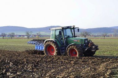 A tractor with a plough, ploughing the soil after the 2010 beet harvest, Northern Germany