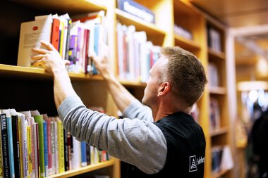 Bibliotekansatt setter bøker i hyller