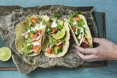 Tortilla med røkelaks, avokado, agurk, spirer, rødløk, koriander, lime og rømme - med hånd