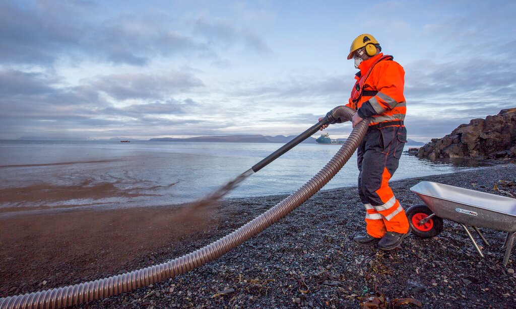 Bark sprøytes på stranda for å innkapsle den simulerte oljen under oljevernøvelsen Øvelse Svalbard onsdag.